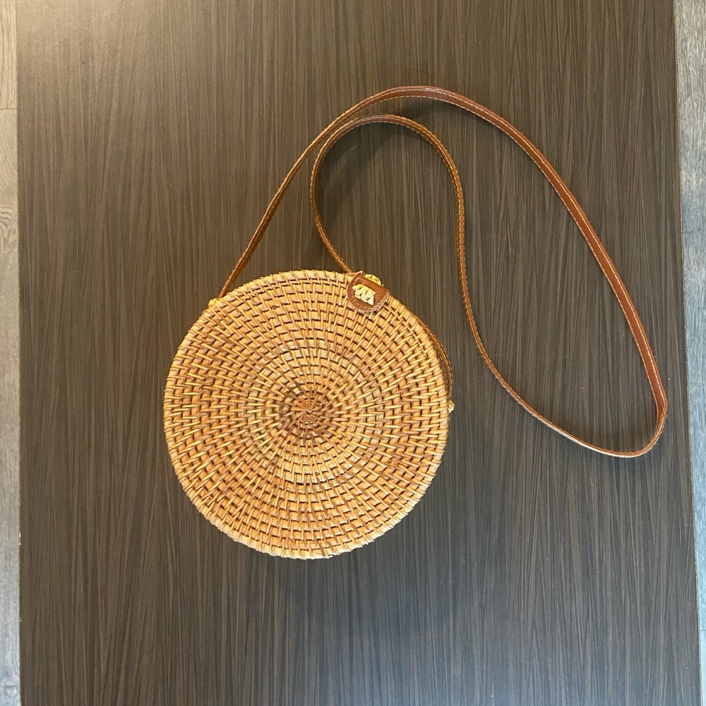 tan and cream round woven straw bag with leather strap with floral inside